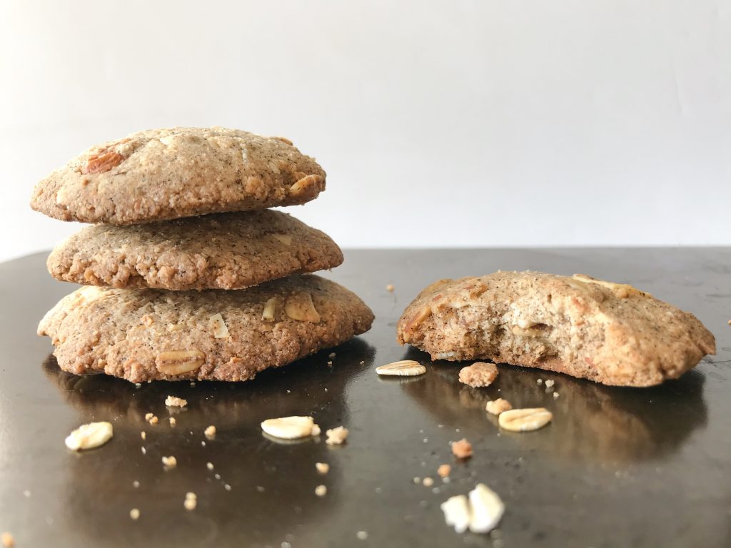 a stack of cardamom oat cookies on a dark tray
