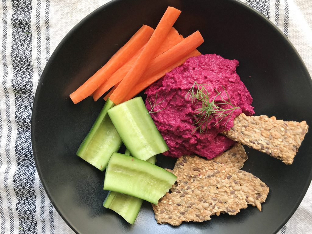 roasted beet and fennel hummus, black bowl, seed crackers, carrot sticks and cucumber boats