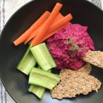 roasted beet and fennel hummus, black bowl, seed crackers, carrot sticks and cucumber boats