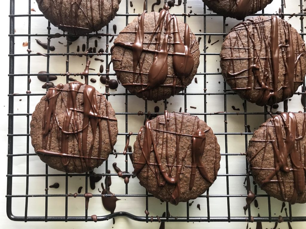 chocolate cookies drizzled with melted chocolate on a black cooling rack